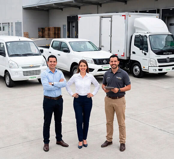Equipo de expertos sonriendo frente a una diversa flota de vehículos comerciales en un centro logístico, representando el respaldo y la experiencia de Grupo Cibest en el alquiler para empresas