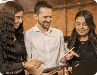 Tres profesionales colaborando y sonriendo, reflejando el excelente ambiente laboral de nuestro equipo